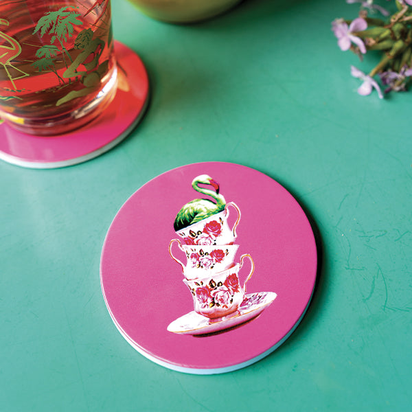 Set of four ceramic coasters in pink depicting three teacups stacked with an exotic bird on top