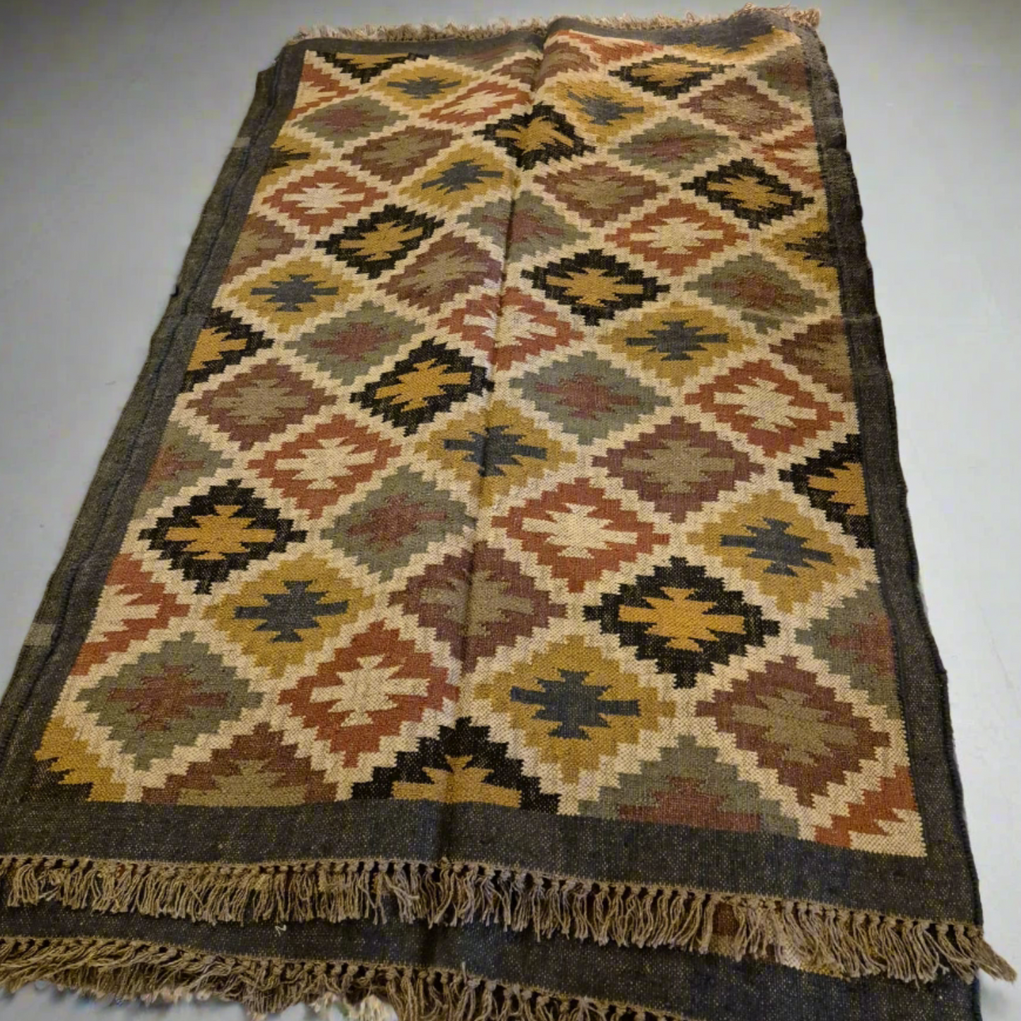 Add a touch of classic elegance to your space with this Kilim Rug (style E2). Handcrafted with jute for a rich and textured look, this 6x4ft rug boasts a beautiful earthy color palette that will bring warmth to any room.