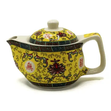 small yellow tea pot with strainer has a yellow oriental motif