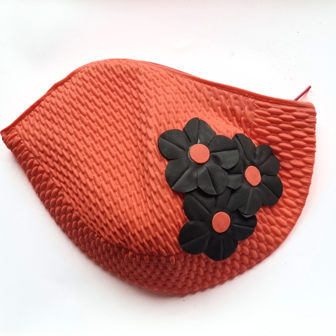 Fuchsia retro swim bag made from a vintage style swimming hat. It has three black flowers on the side.