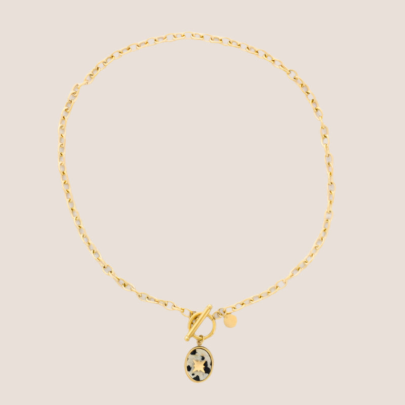 Gold bracelet with a small pendant on a light gray background